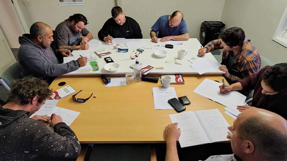 Students around a table, sitting driver licence test, using pen and paper.